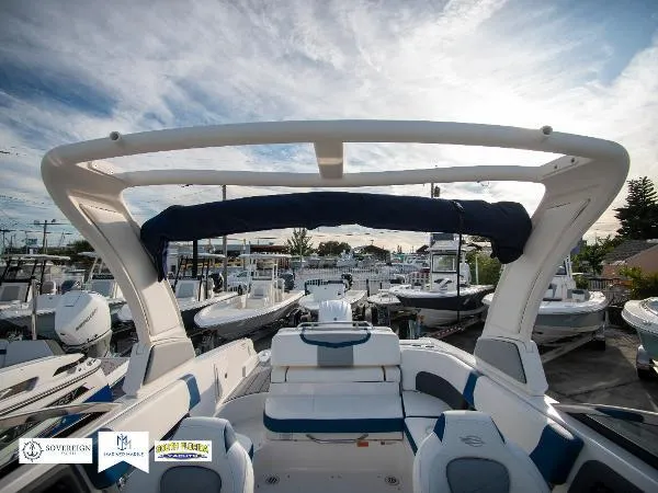 Slide: The Image of 2024 Chaparral 270 OSX boat with sleek design, docked among other vessels under a blue sky. - 27