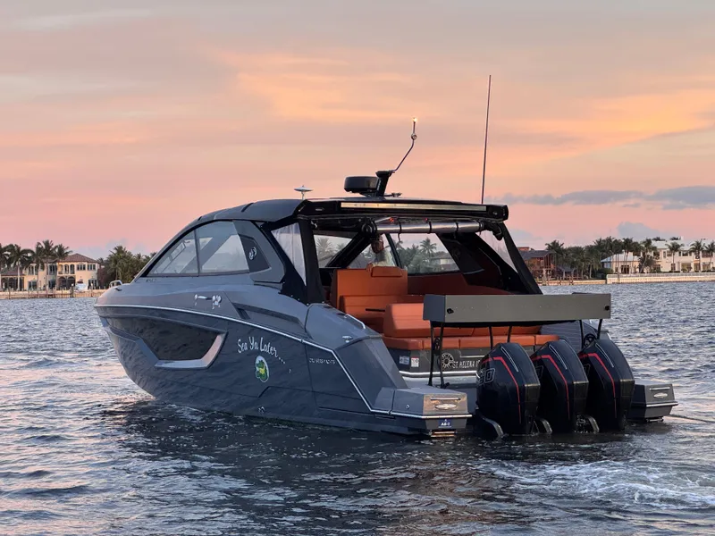 Slide: The Image of 2021 Cruisers Yachts 42 GLS OB on water at sunset, featuring triple outboard engines. - 0