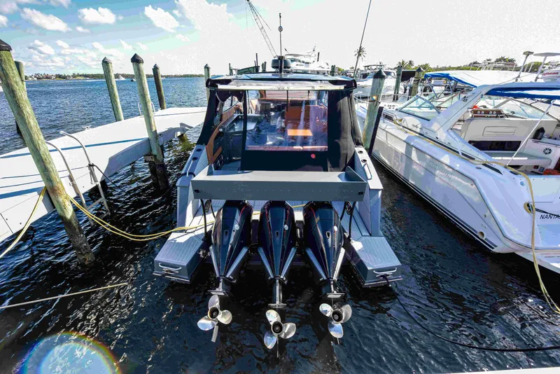 Slide: The Image of 2021 Cruisers Yachts 42 GLS OB docked, featuring triple outboard engines, under a clear blue sky. - 6