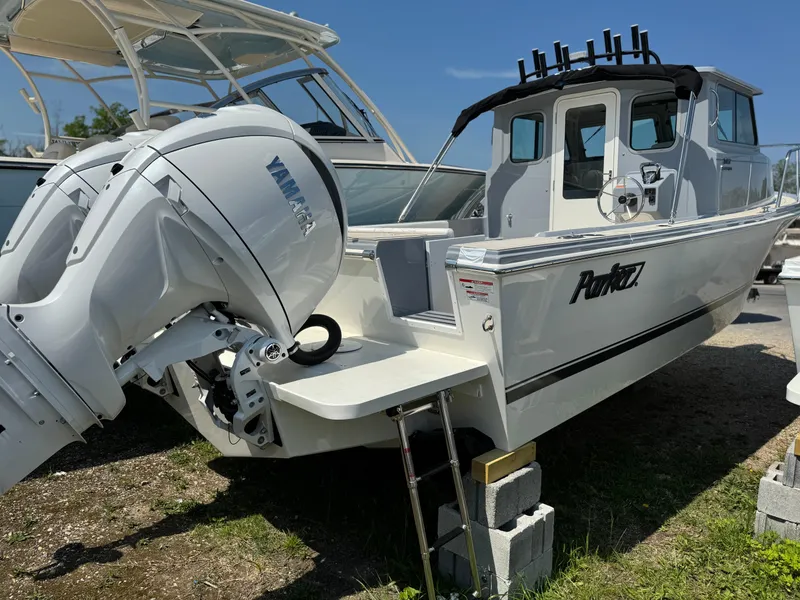 Slide: The Image of 2025 Parker 2520 XLD Sport Cabin boat with Yamaha outboard motor, docked on land. - 1