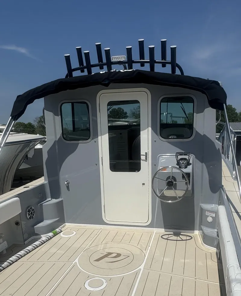Slide: The Image of 2025 Parker 2520 XLD Sport Cabin boat with steering wheel and rod holders. - 2