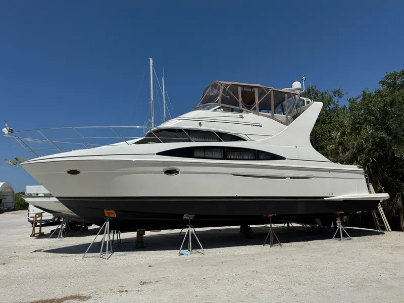 The Image of 2004 Carver 420 Mariner yacht on stands, displayed outdoors under clear blue sky. - 0