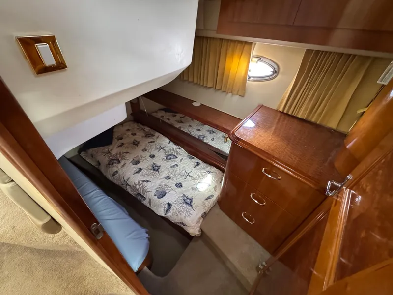 Slide: The Image of 2004 Carver 420 Mariner cabin interior with bed, wooden cabinetry, and porthole window. - 9