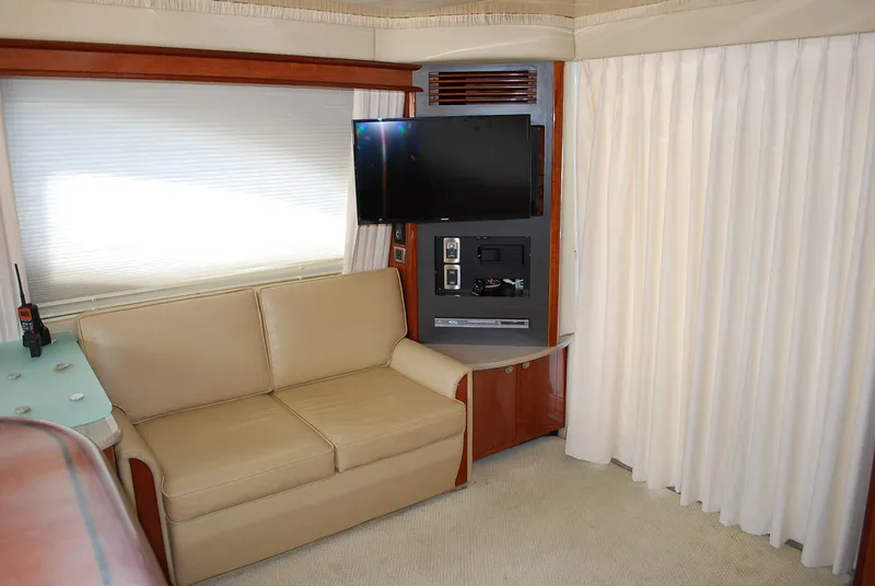 Slide: The Image of 2004 Sea Ray Sedan Bridge interior with beige sofa, TV, and curtains. - 15