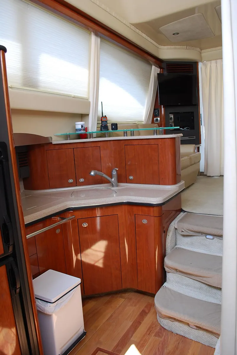 Slide: The Image of 2004 Sea Ray Sedan Bridge interior with wooden cabinetry, modern kitchen, and carpeted stairs. - 19