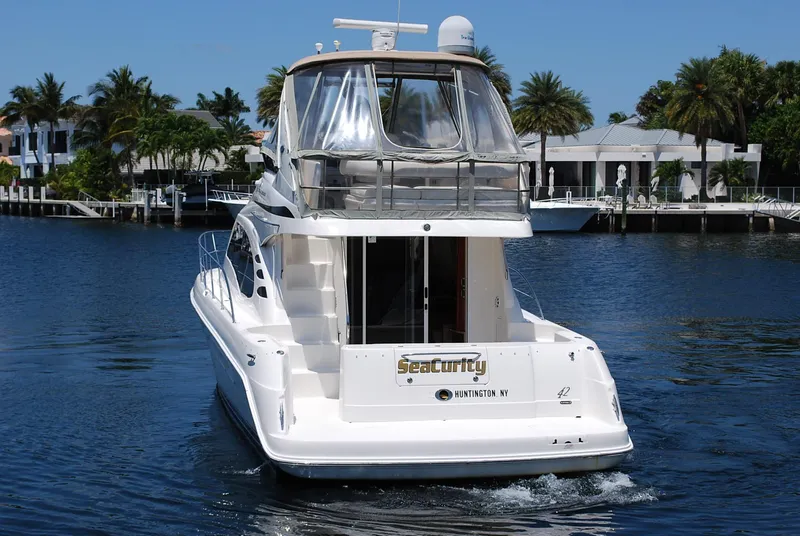 Slide: The Image of 2004 Sea Ray Sedan Bridge yacht on calm water, surrounded by palm trees and waterfront homes. - 3