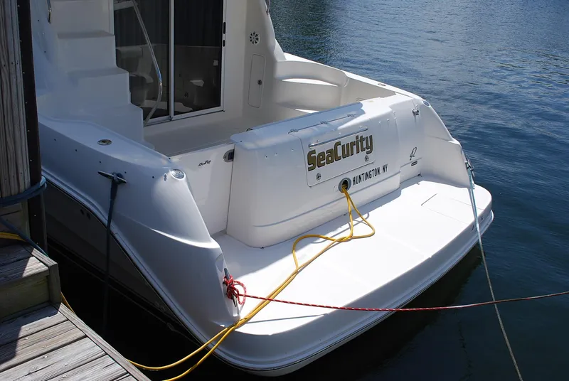 Slide: The Image of 2004 Sea Ray Sedan Bridge yacht docked, rear view with ropes and water background. - 4