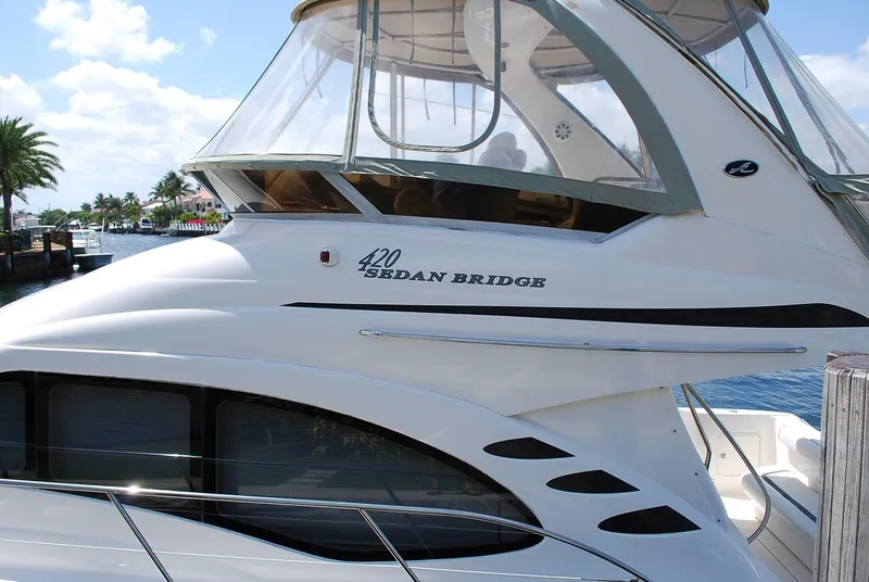 Slide: The Image of 2004 Sea Ray Sedan Bridge yacht docked by the water, featuring sleek design and spacious cabin. - 6