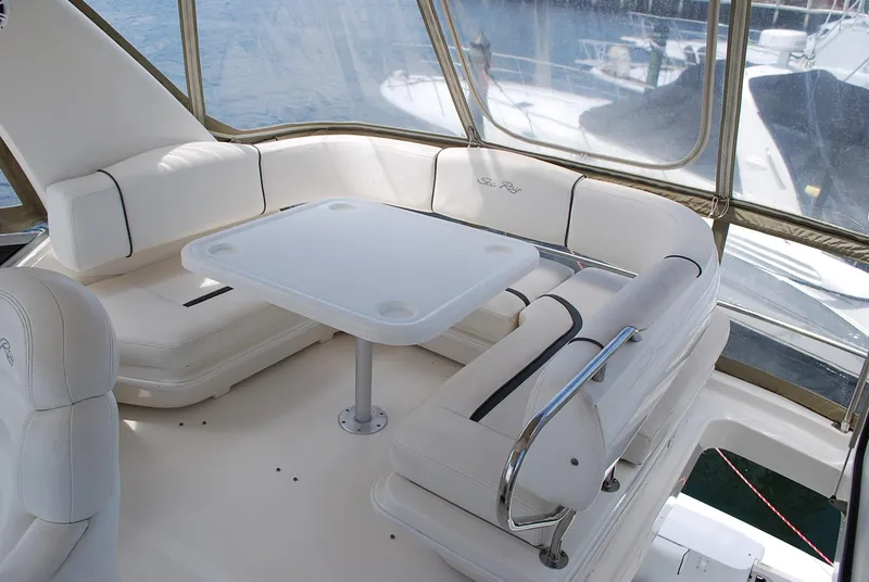 Slide: The Image of 2004 Sea Ray Sedan Bridge interior with white seating and table, overlooking water. - 9