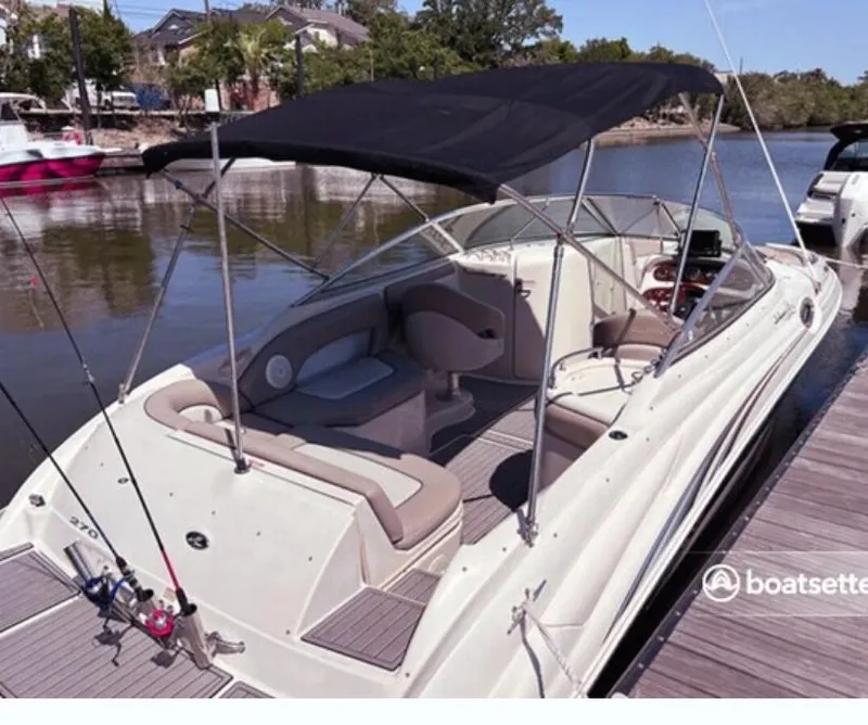Slide: The Image of 2004 Sea Ray 270 Sundeck boat docked, featuring spacious seating and a black canopy. - 2