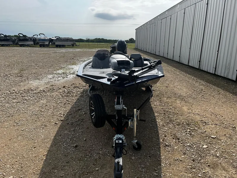 Slide: The Image of 2025 G3 Sportsman 1710 boat on trailer, parked on gravel near a large building. - 2