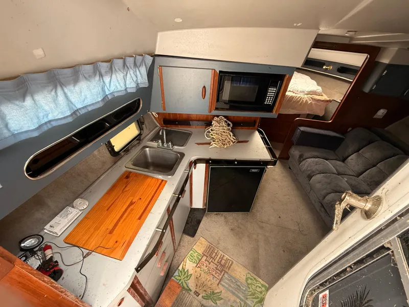 Slide: The Image of Interior of 1986 Cruisers 337 boat with kitchenette, sink, microwave, and seating area. - 12