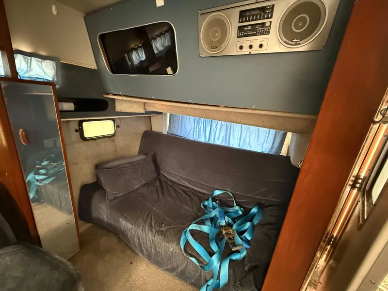 Slide: The Image of Interior of a 1986 Cruisers 337 boat with a sofa, speakers, and blue straps. - 14