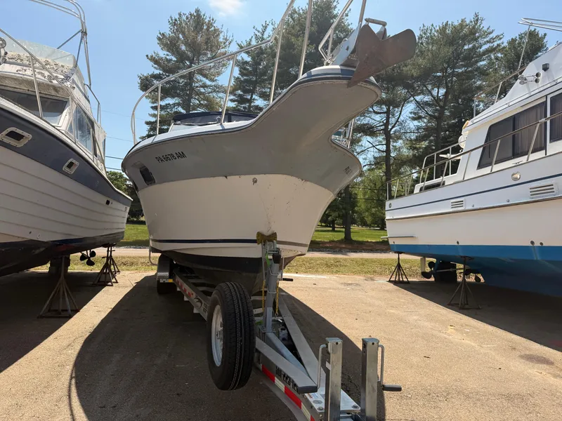 Slide: The Image of 1986 Cruisers 337 boat on trailer, parked outdoors between two other boats. - 3