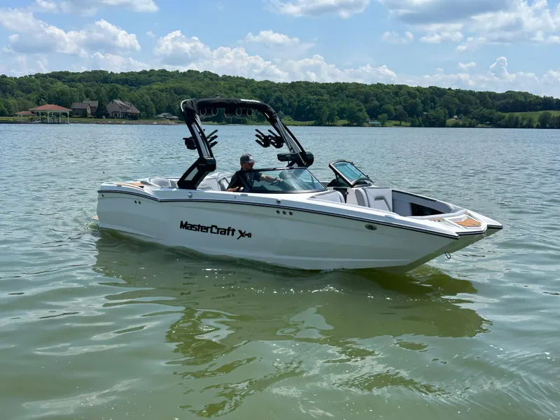 Slide: The Image of 2024 MasterCraft XStar S boat on a lake with scenic background. - 0