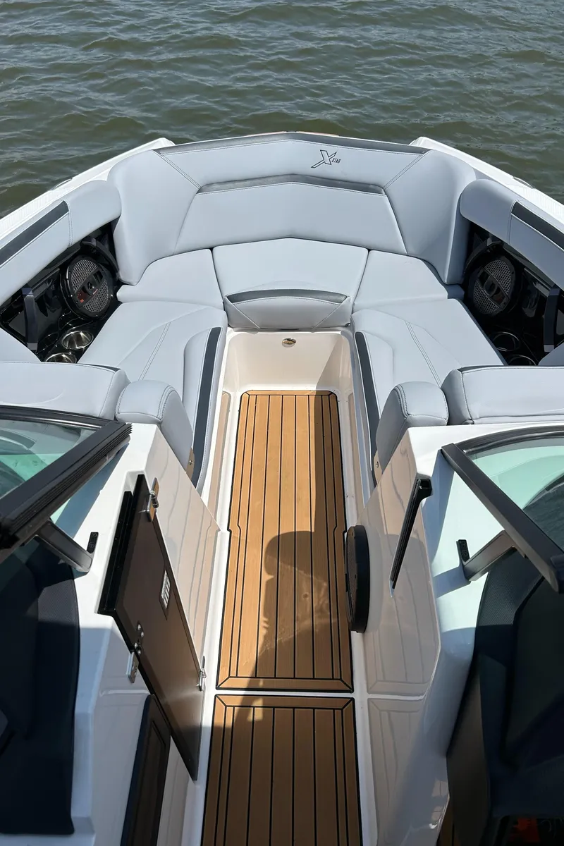 Slide: The Image of 2024 MasterCraft XStar S boat interior with sleek seating and wooden flooring on water. - 1