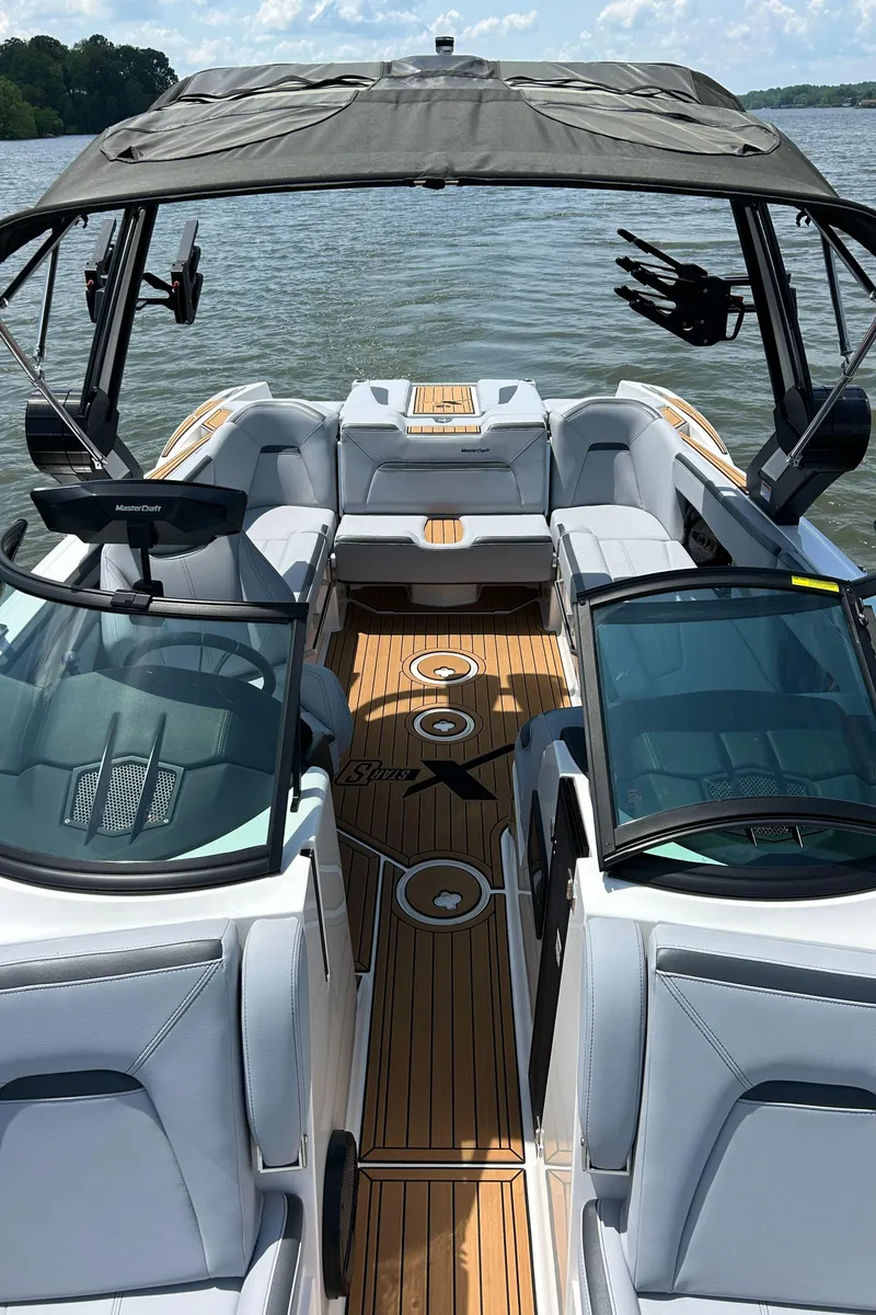 Slide: The Image of 2024 MasterCraft XStar S boat interior with sleek seating and modern design on a sunny lake. - 2