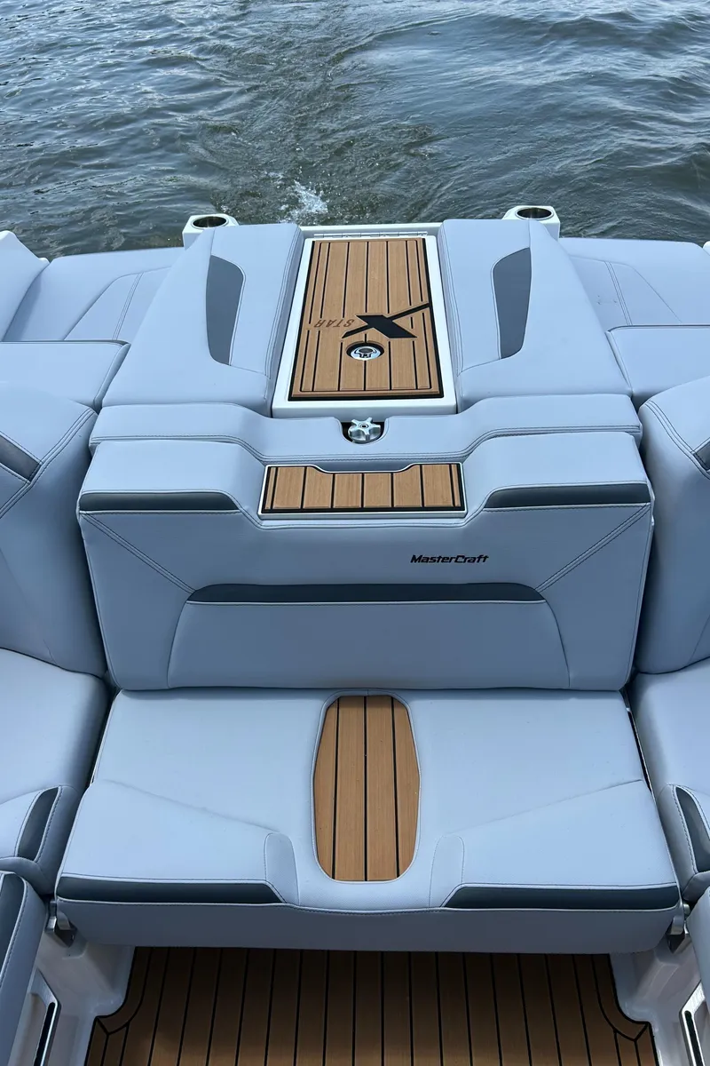 Slide: The Image of 2024 MasterCraft XStar S boat with sleek seating and teak accents on the water. - 9