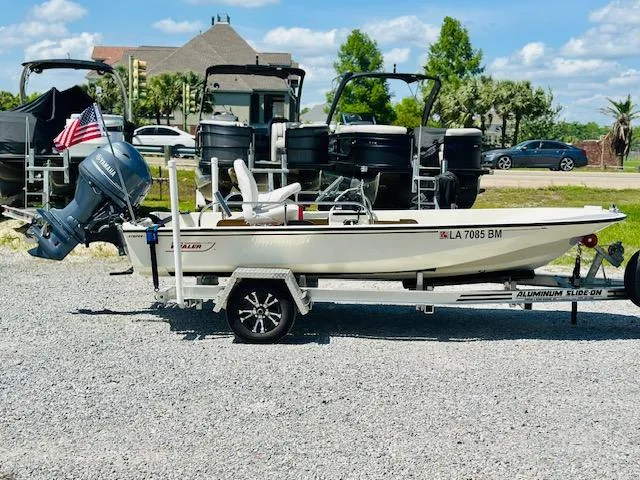 Slide: The Image of 1986 Boston Whaler 150 Sport boat on trailer, parked outdoors, with American flag. - 1