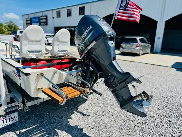 Slide: The Image of 1986 Boston Whaler 150 Sport with Yamaha outboard motor and American flag, parked on gravel. - 6