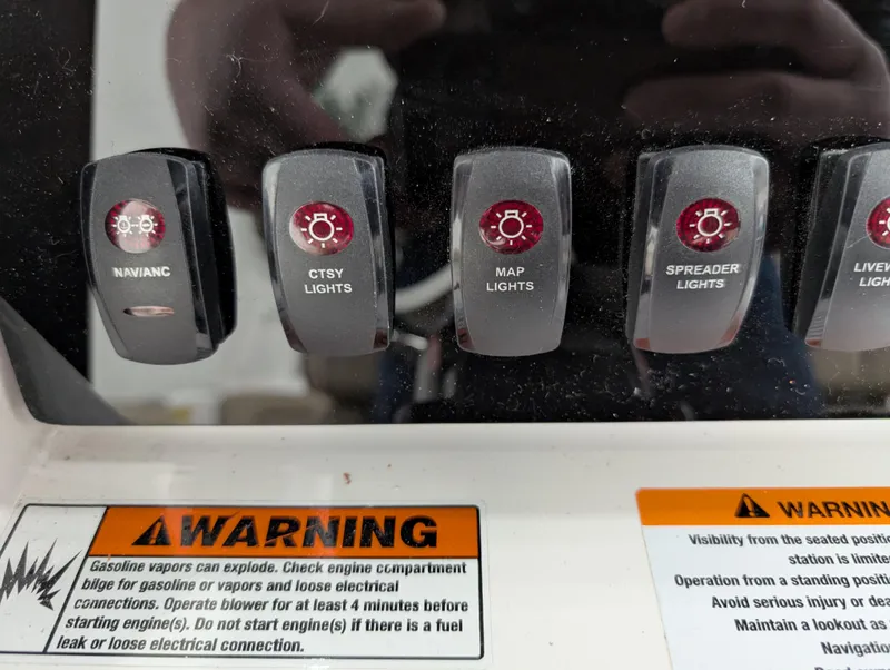 Slide: The Image of Control panel of 2024 Yamaha Boats 255 FSH Sport H with warning labels and light switches. - 10