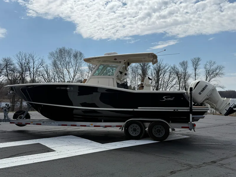 Slide: The Image of 2016 Scout 300 LXF boat on trailer, parked outdoors under cloudy sky. - 2