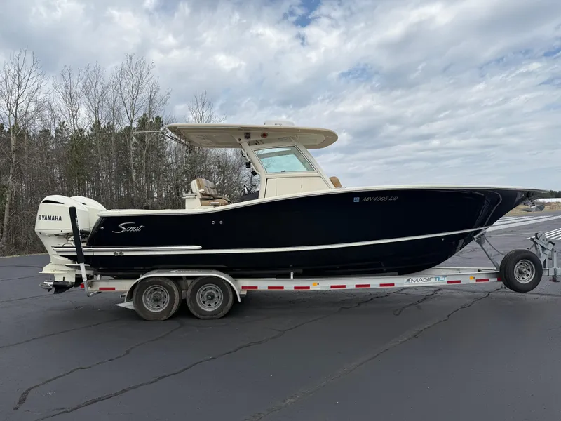 Slide: The Image of 2016 Scout 300 LXF boat on trailer, black hull, parked outdoors under cloudy sky. - 6