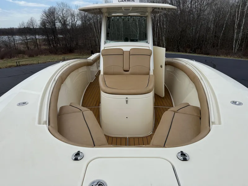 Slide: The Image of 2016 Scout 300 LXF boat with tan seating and Garmin equipment, docked near a wooded area. - 9