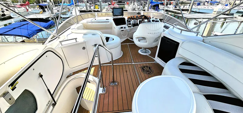 Slide: The Image of 2007 Meridian 341 Sedan yacht interior with seating, helm, and wood flooring at a marina. - 17