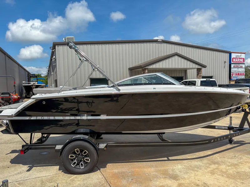 The Image of 2023 Four Winns H1 boat on trailer, parked outside a warehouse under a blue sky. - 0