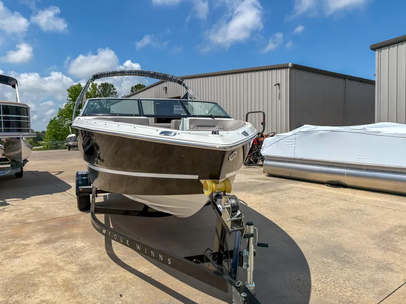 Slide: The Image of 2023 Four Winns H1 boat on trailer, parked outdoors under a clear blue sky. - 4