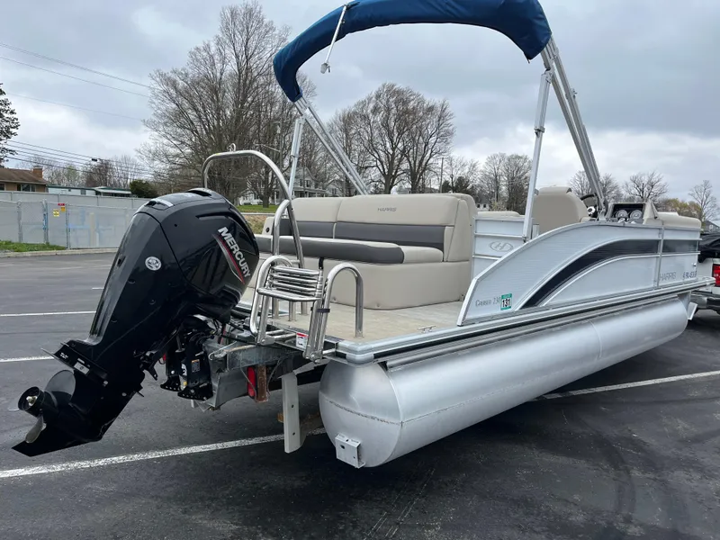 Slide: The Image of 2022 Harris Cruiser 230 pontoon boat with Mercury outboard motor, parked on asphalt. - 10