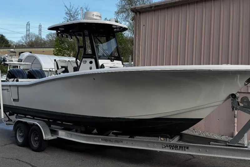 Slide: The Image of 2023 Tidewater 272 LXF boat on trailer, parked outdoors near a building. - 0