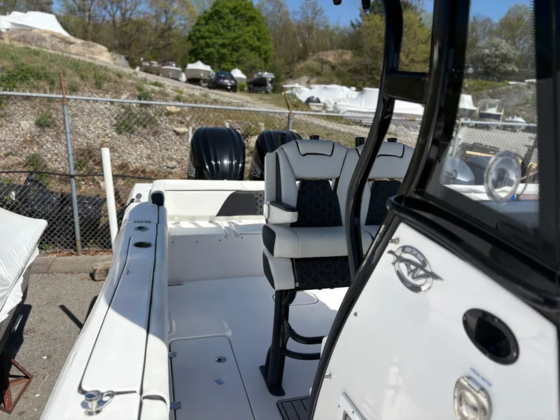 Slide: The Image of 2023 Tidewater 272 LXF boat interior with dual seats and console, parked outdoors. - 13