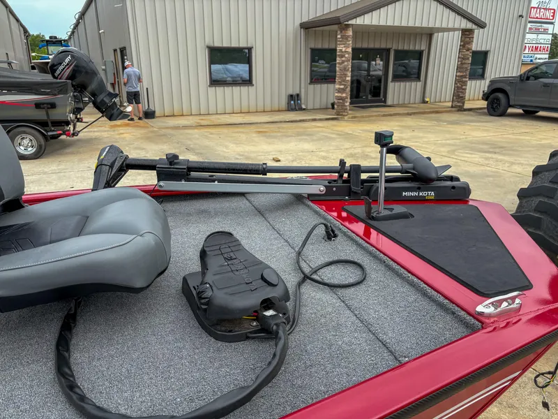 Slide: The Image of 2024 Tracker Pro 170 boat with Minn Kota trolling motor and gray seating, parked outside a building. - 12