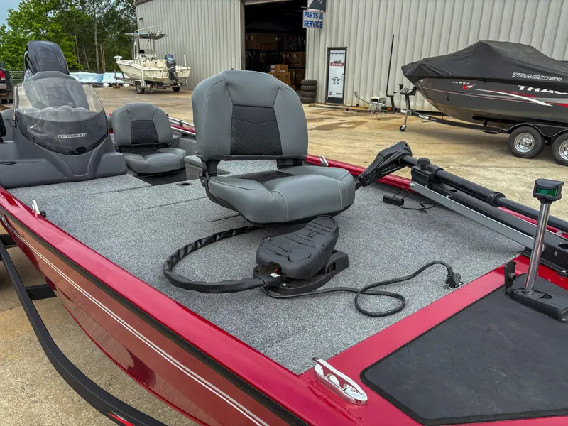 Slide: The Image of 2024 Tracker Pro 170 boat with gray seating and red trim, parked near a service area. - 13