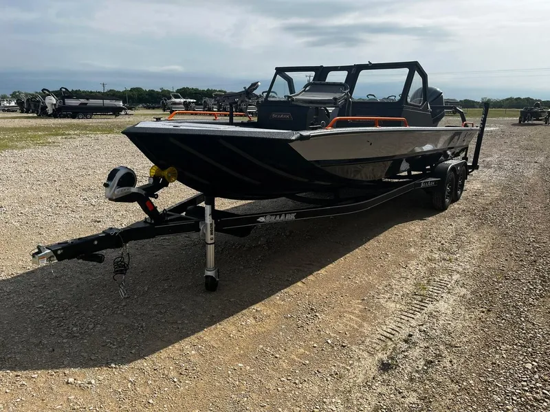 Slide: The Image of 2025 SeaArk ProCat 240 boat on trailer, parked on gravel lot under cloudy sky. - 3