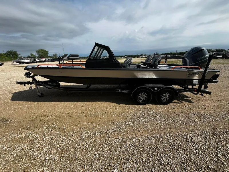 Slide: The Image of 2025 SeaArk ProCat 240 boat on a trailer, parked on gravel under a cloudy sky. - 4