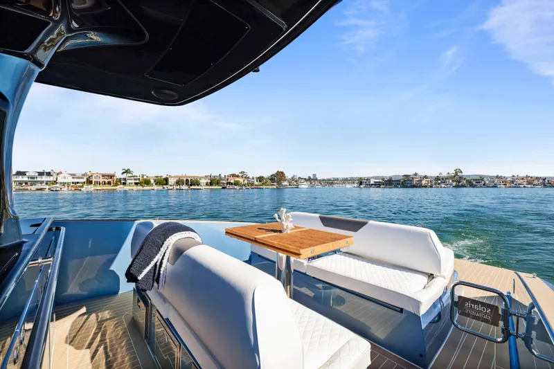 Slide: The Image of 2023 Solaris Power 40 Open yacht interior with seating and table, overlooking serene waterfront. - 14