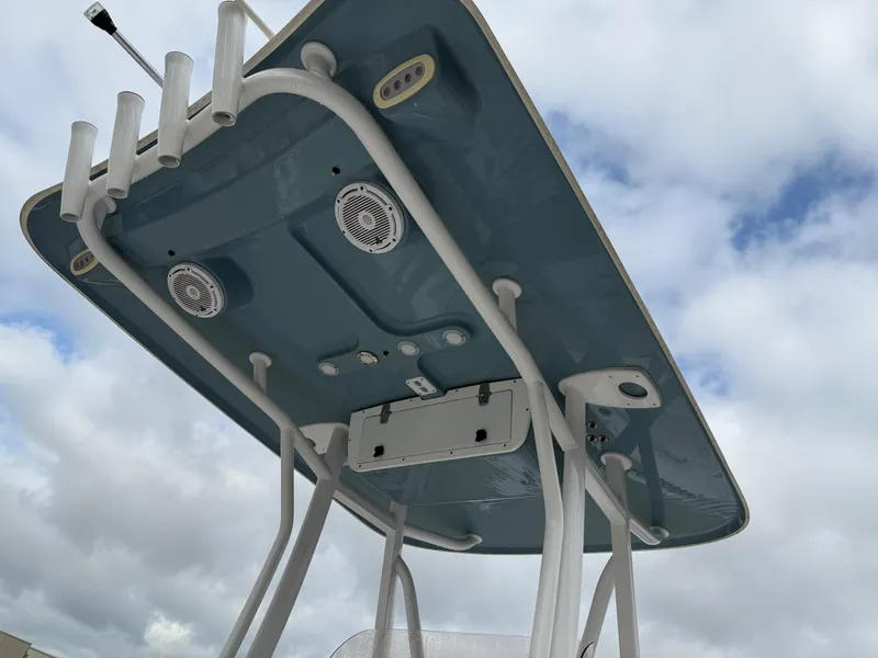 Slide: The Image of 2021 Sea Hunt Ultra 219 T-top with rod holders and speakers against cloudy sky. - 11
