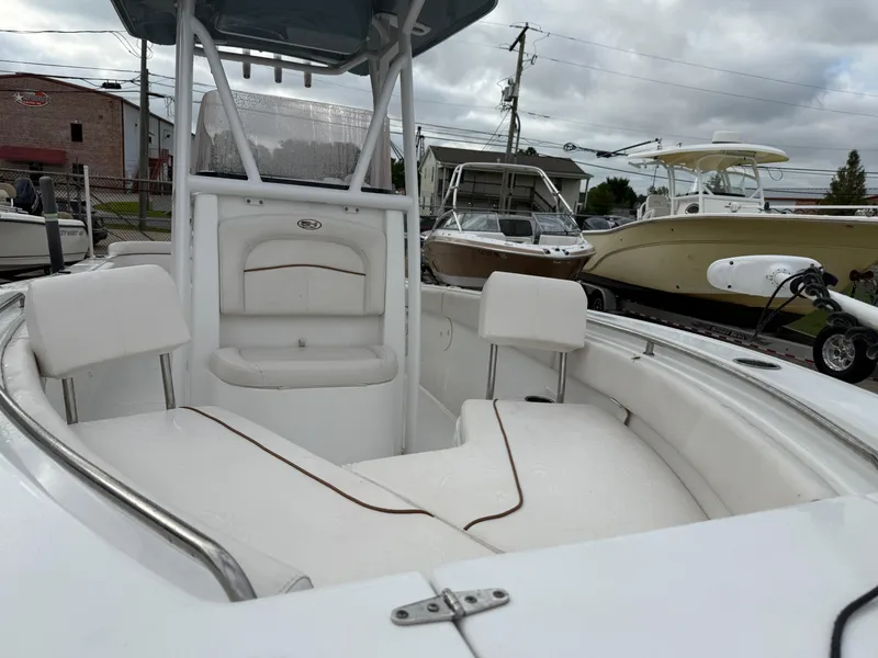 Slide: The Image of 2021 Sea Hunt Ultra 219 boat with white seating and center console, docked outdoors. - 22