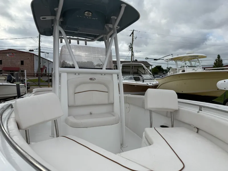 Slide: The Image of 2021 Sea Hunt Ultra 219 boat with white seating and center console, docked under cloudy skies. - 23