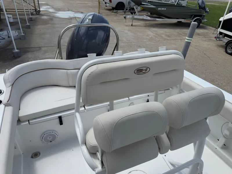 Slide: The Image of 2021 Sea Hunt Ultra 219 boat interior with cushioned seating and motor view. - 27