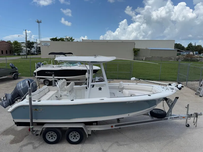 Slide: The Image of 2021 Sea Hunt Ultra 219 boat on trailer, parked outdoors under a cloudy sky. - 4
