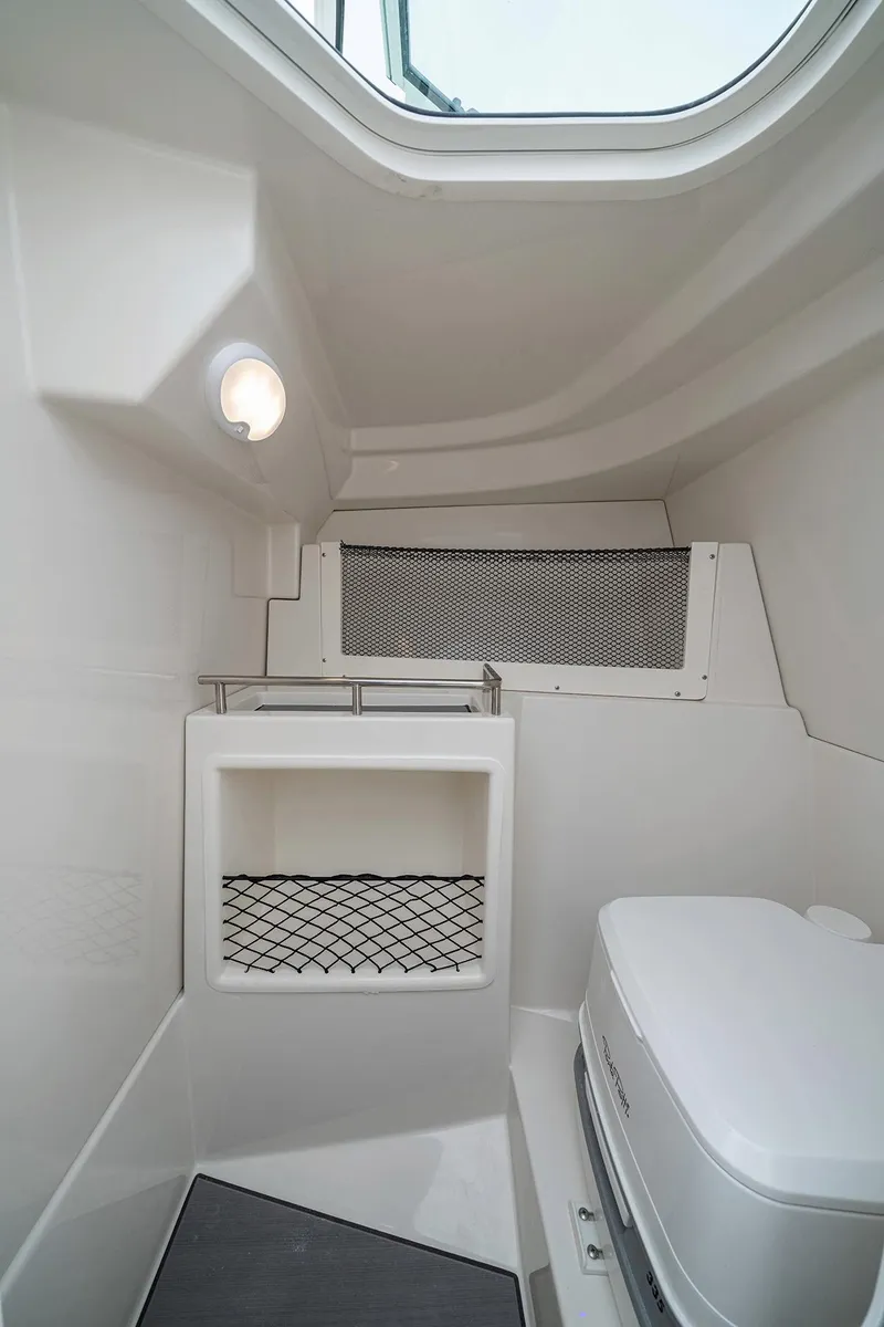 Slide: The Image of Interior of 2026 Sailfish 236 DC boat, featuring compact bathroom with toilet and storage. - 18