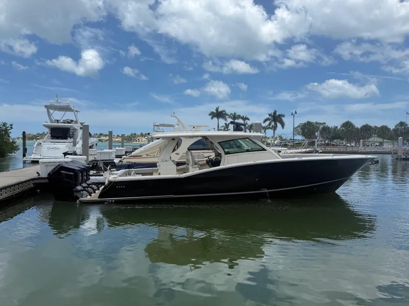 The Image of 2022 Scout 425 LXF boat docked in a marina under a partly cloudy sky. - 0