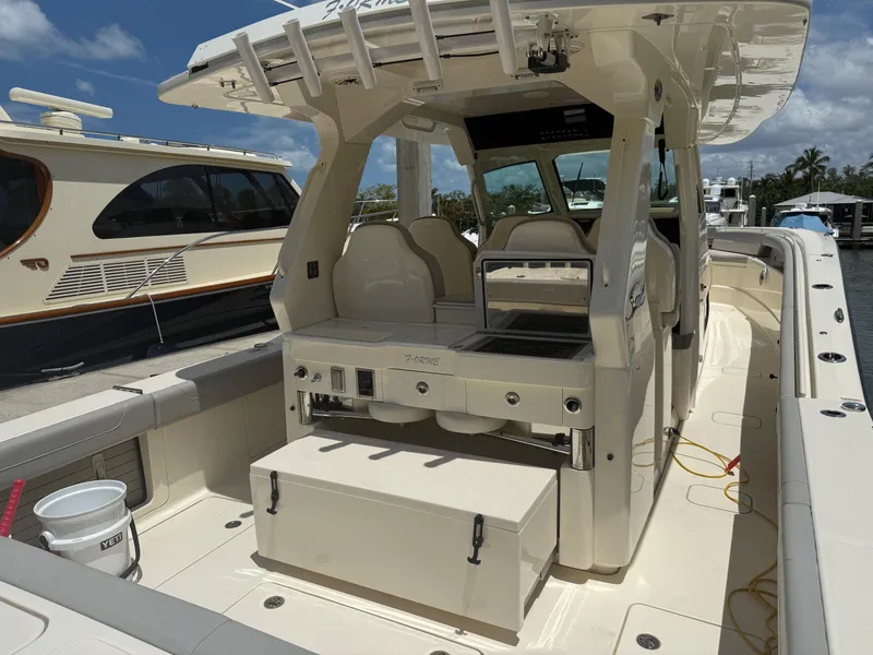 Slide: The Image of 2022 Scout 425 LXF boat interior with seating and storage, docked under a clear sky. - 11
