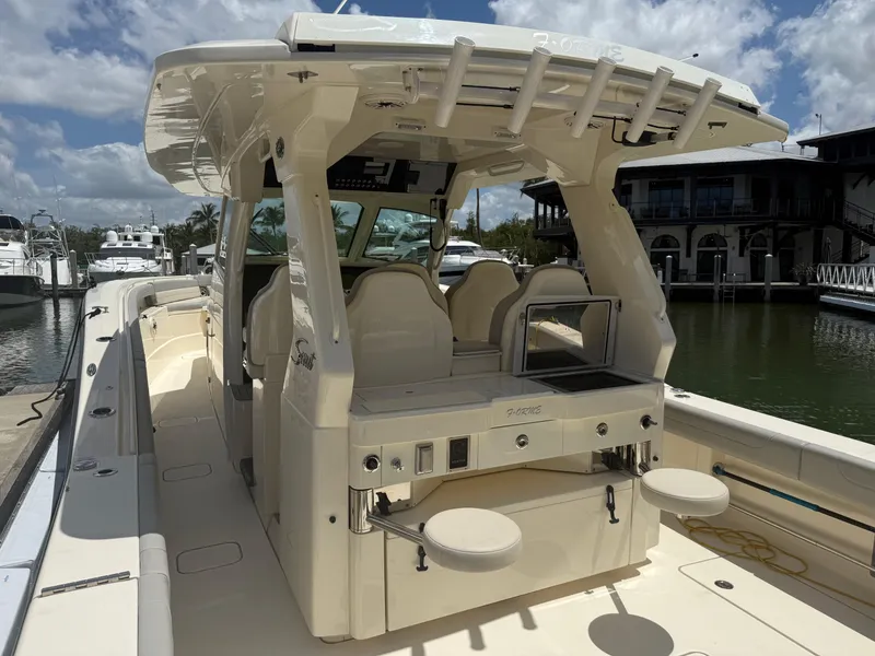 Slide: The Image of 2022 Scout 425 LXF boat with spacious deck and seating, docked at marina under blue sky. - 13