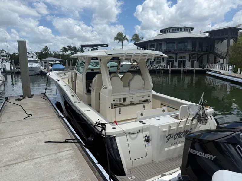 Slide: The Image of 2022 Scout 425 LXF boat docked at marina with Mercury engine, under cloudy sky. - 4