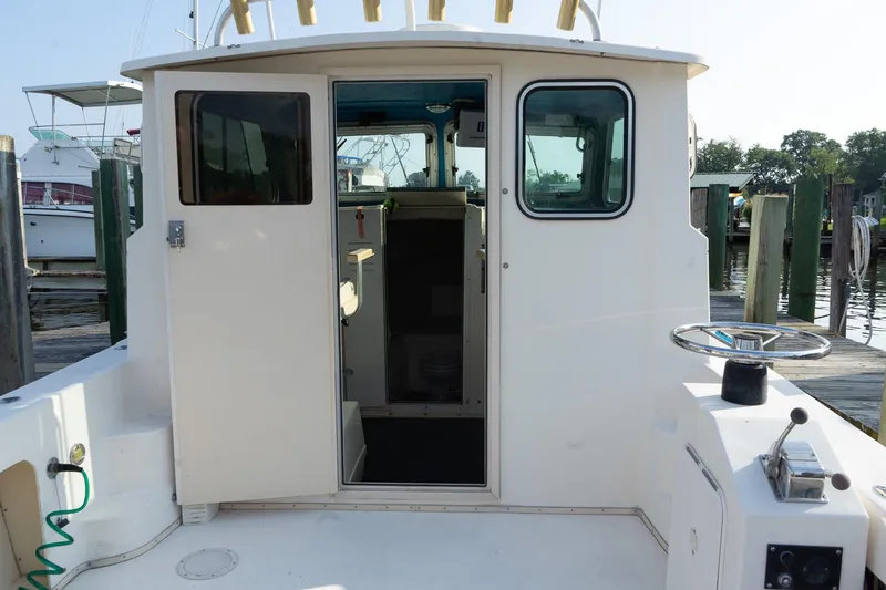 Slide: The Image of 2005 Parker 2520 Deep Vee Sport Cabin boat at dock, open cabin door, steering wheel visible. - 21